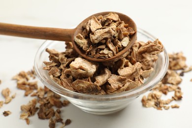 Photo of Pieces of dry chicory roots in bowl and spoon on white table, closeup