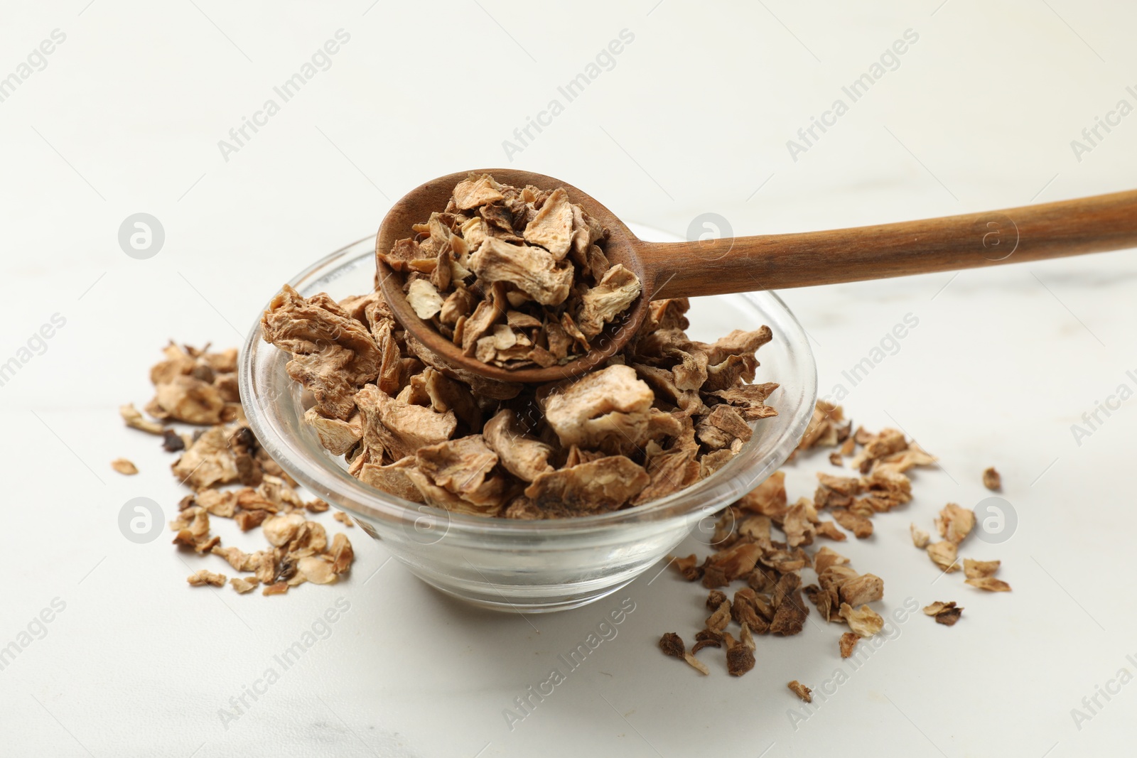 Pieces of dry chicory roots in bowl and spoon on white table, closeup Photo of Pieces of dry chicory roots in bowl and spoon on white table, closeup