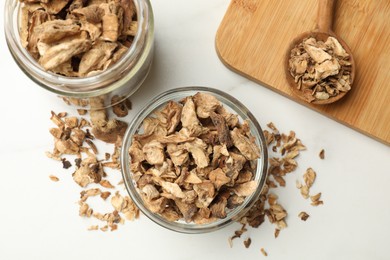 Photo of Pieces of dry chicory roots in bowl, jar and spoon on white table, flat lay