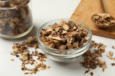 Photo of Pieces of dry chicory roots in bowl, jar and spoon on white table, closeup
