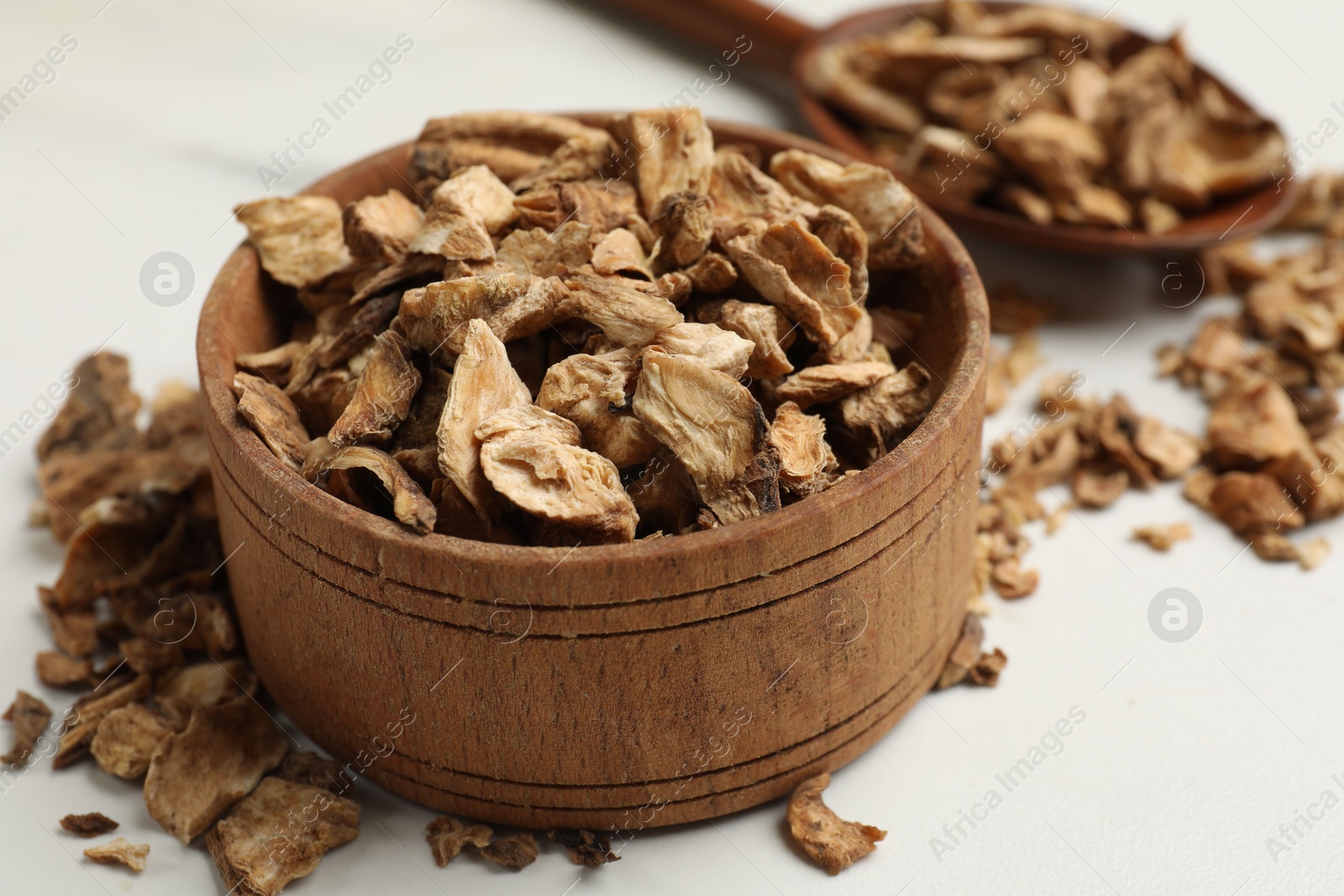 Pieces of dry chicory roots in bowl and spoon on white table, closeup Photo of Pieces of dry chicory roots in bowl and spoon on white table, closeup