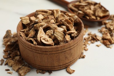 Photo of Pieces of dry chicory roots in bowl and spoon on white table, closeup