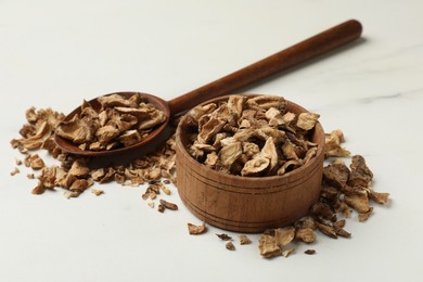 Photo of Pieces of dry chicory roots in bowl and spoon on white table