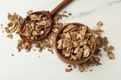 Photo of Pieces of dry chicory roots in bowl and spoon on white table, flat lay