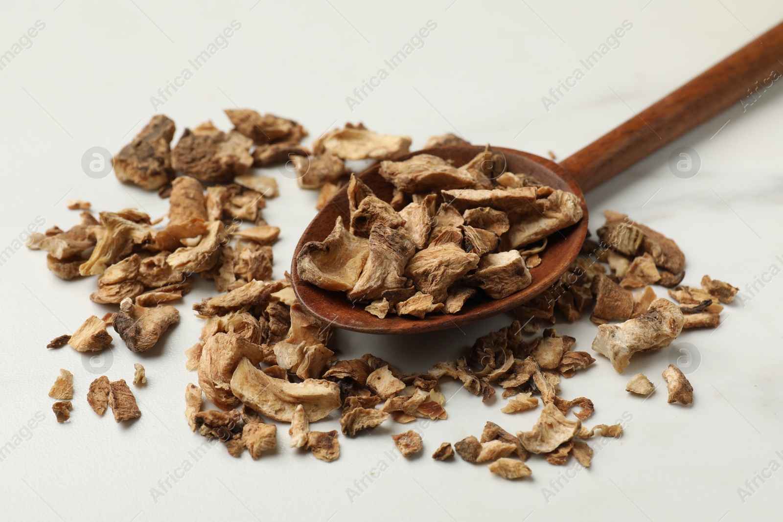 Pieces of dry chicory roots in spoon on white table, closeup Photo of Pieces of dry chicory roots in spoon on white table, closeup