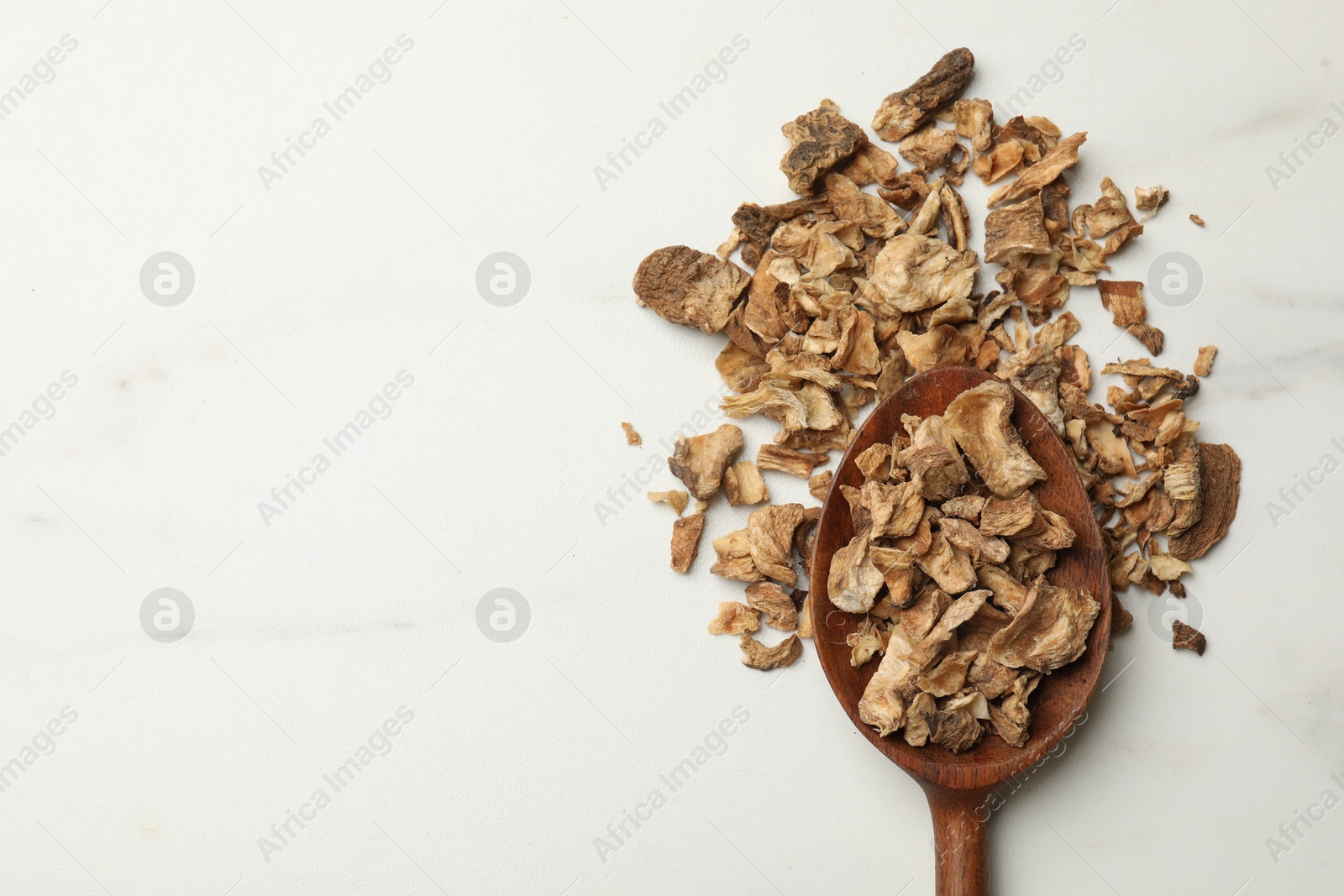 Pieces of dry chicory roots in spoon on white table, top view. Space for text Photo of Pieces of dry chicory roots in spoon on white table, top view. Space for text