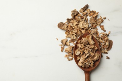 Photo of Pieces of dry chicory roots in spoon on white table, top view. Space for text