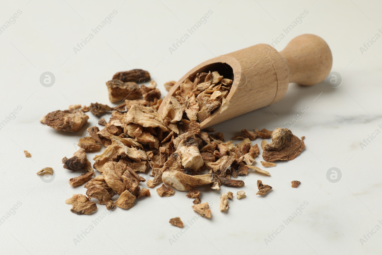Pieces of dry chicory roots and scoop on white table Photo of Pieces of dry chicory roots and scoop on white table