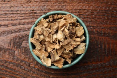 Photo of Pieces of dry chicory roots in bowl on wooden table, top view