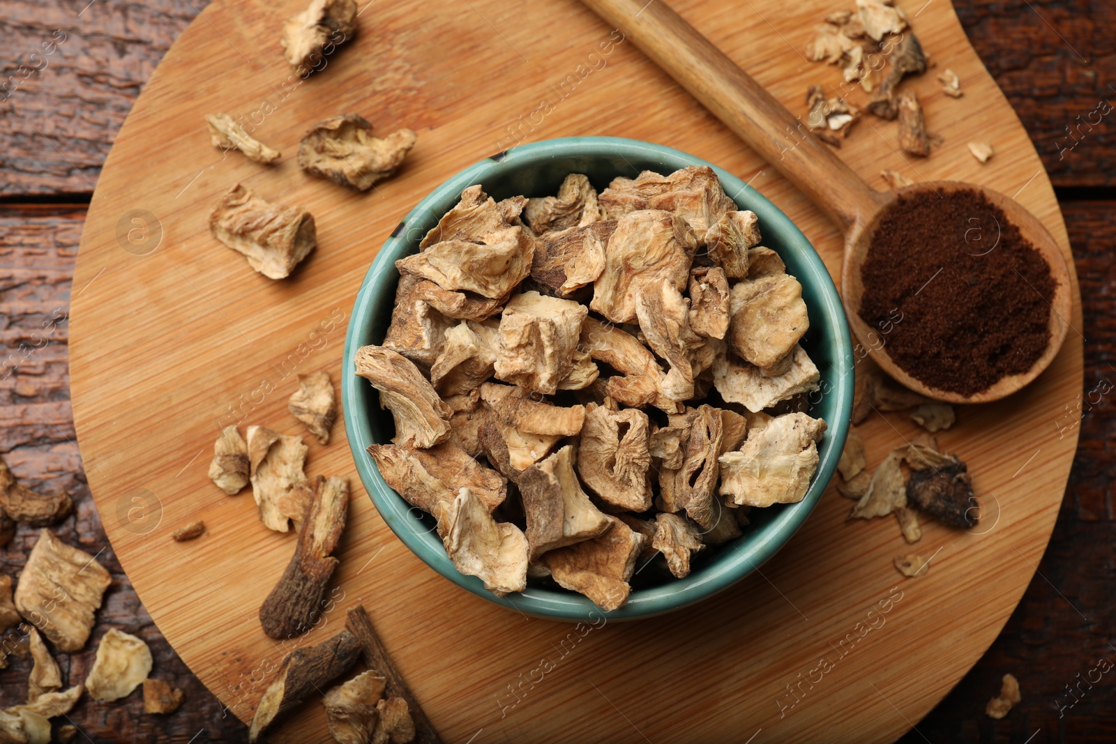 Pieces of dry chicory roots in bowl and spoon with powder on wooden table, top view Photo of Pieces of dry chicory roots in bowl and spoon with powder on wooden table, top view