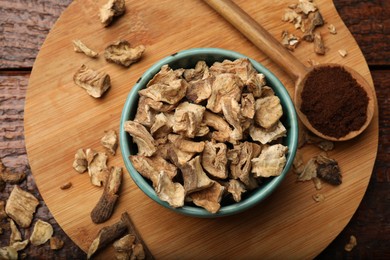 Photo of Pieces of dry chicory roots in bowl and spoon with powder on wooden table, top view