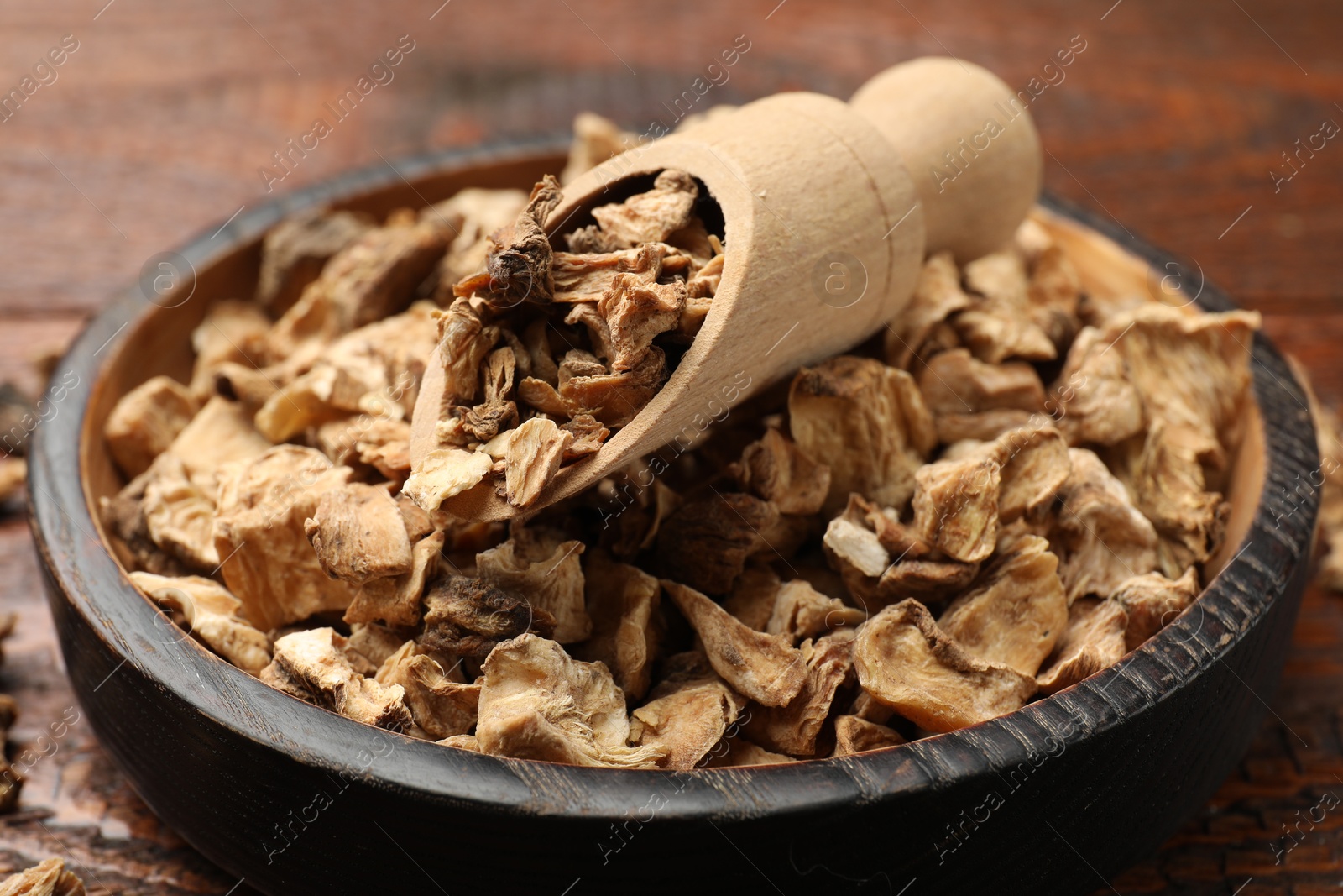 Pieces of dry chicory roots in bowl and scoop on wooden table, closeup Photo of Pieces of dry chicory roots in bowl and scoop on wooden table, closeup