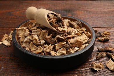 Photo of Pieces of dry chicory roots in bowl and scoop on wooden table, closeup