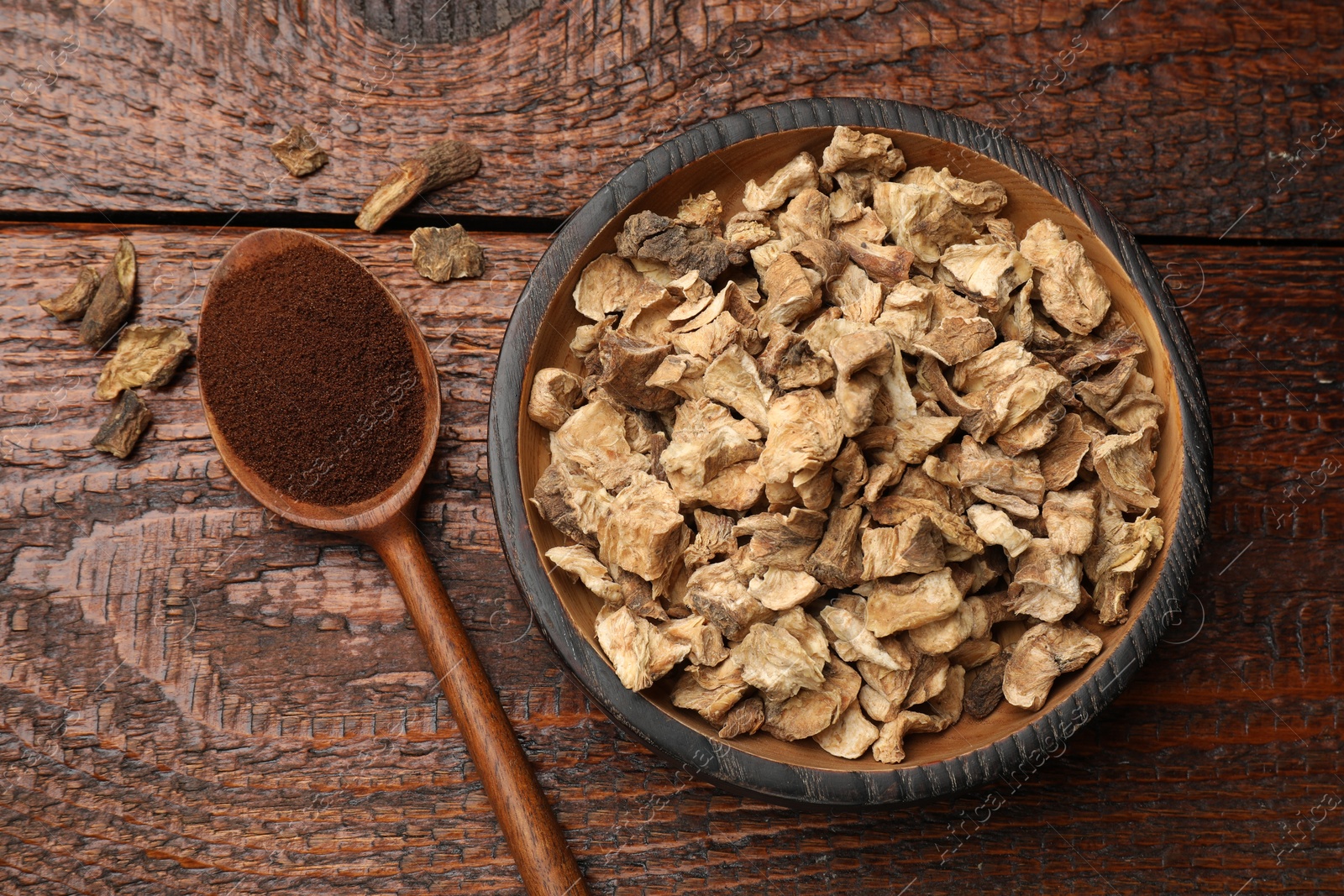 Pieces of dry chicory roots in bowl and spoon with powder on wooden table, flat lay Photo of Pieces of dry chicory roots in bowl and spoon with powder on wooden table, flat lay