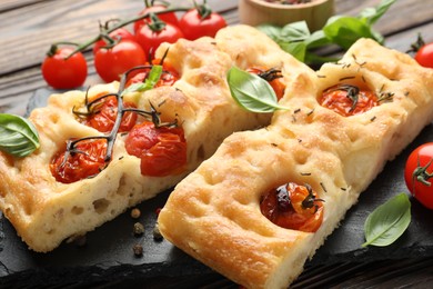 Photo of Pieces of delicious focaccia with tomatoes and spices on table, closeup