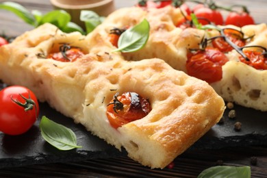 Photo of Pieces of delicious focaccia with tomatoes and spices on table, closeup