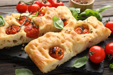 Photo of Pieces of delicious focaccia with tomatoes and spices on table, closeup