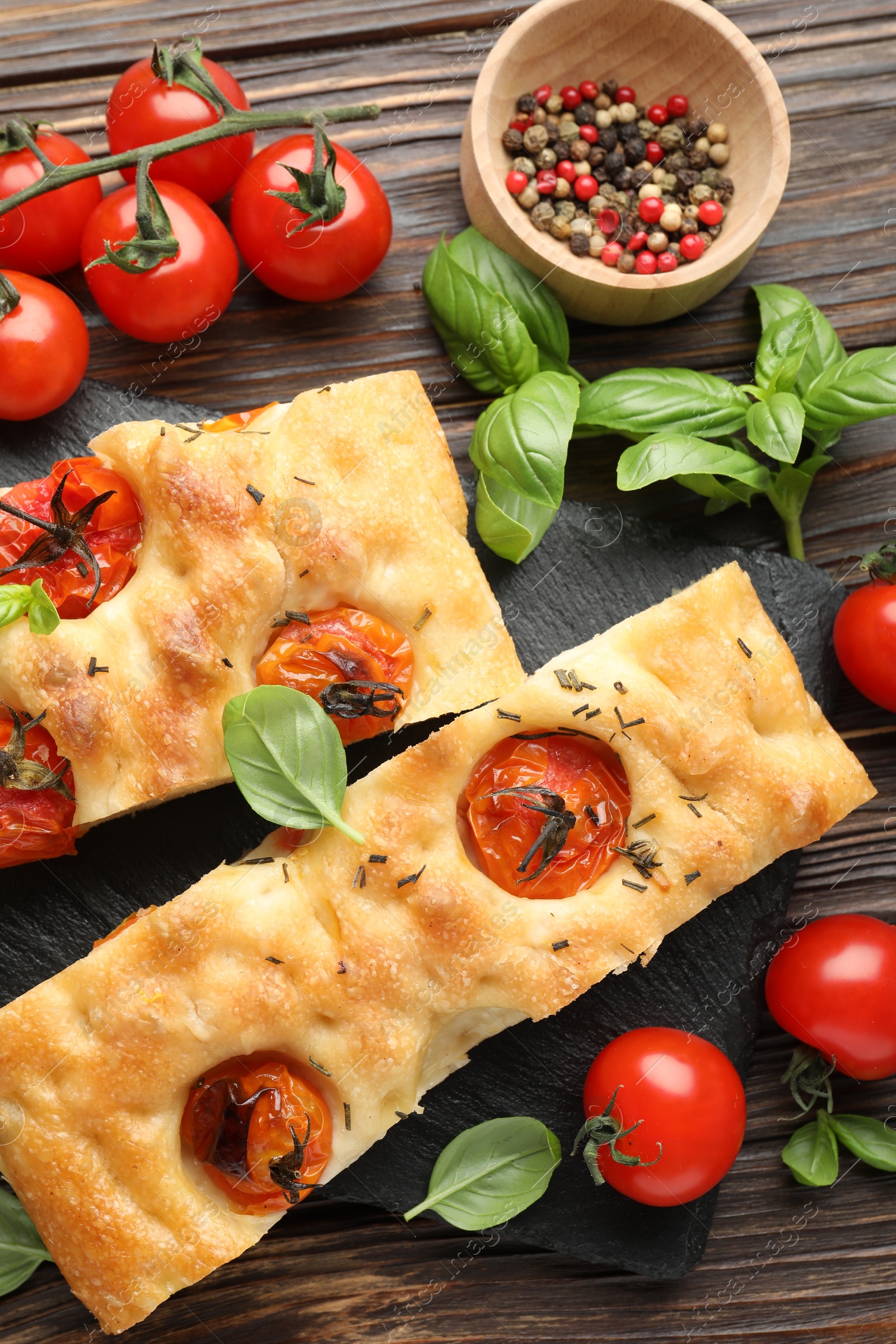 Pieces of delicious focaccia with tomatoes and spices on wooden table, flat lay Photo of Pieces of delicious focaccia with tomatoes and spices on wooden table, flat lay