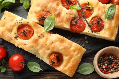 Photo of Pieces of delicious focaccia with tomatoes and spices on table, flat lay