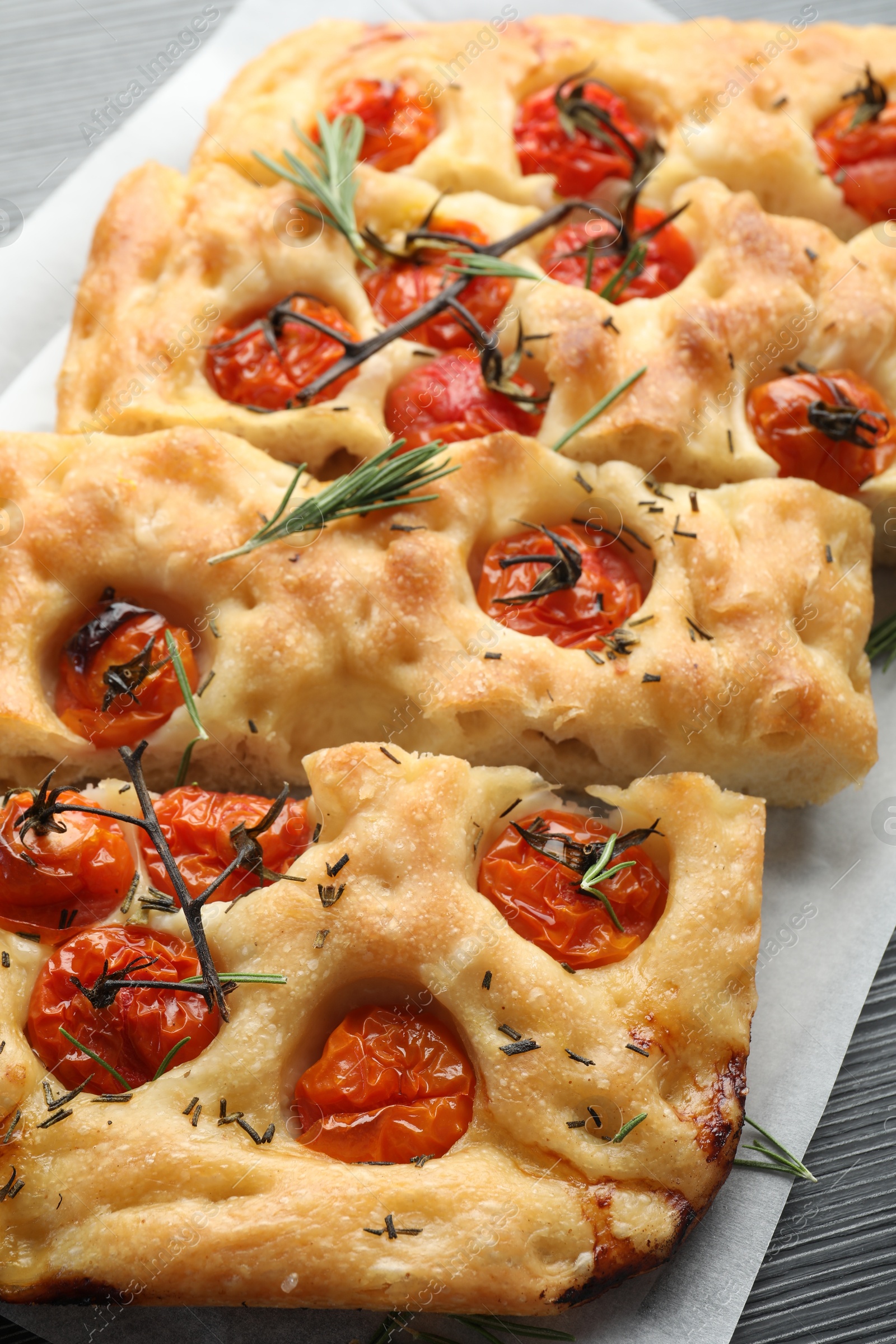 Cut delicious focaccia with tomatoes and spices on table, closeup Photo of Cut delicious focaccia with tomatoes and spices on table, closeup