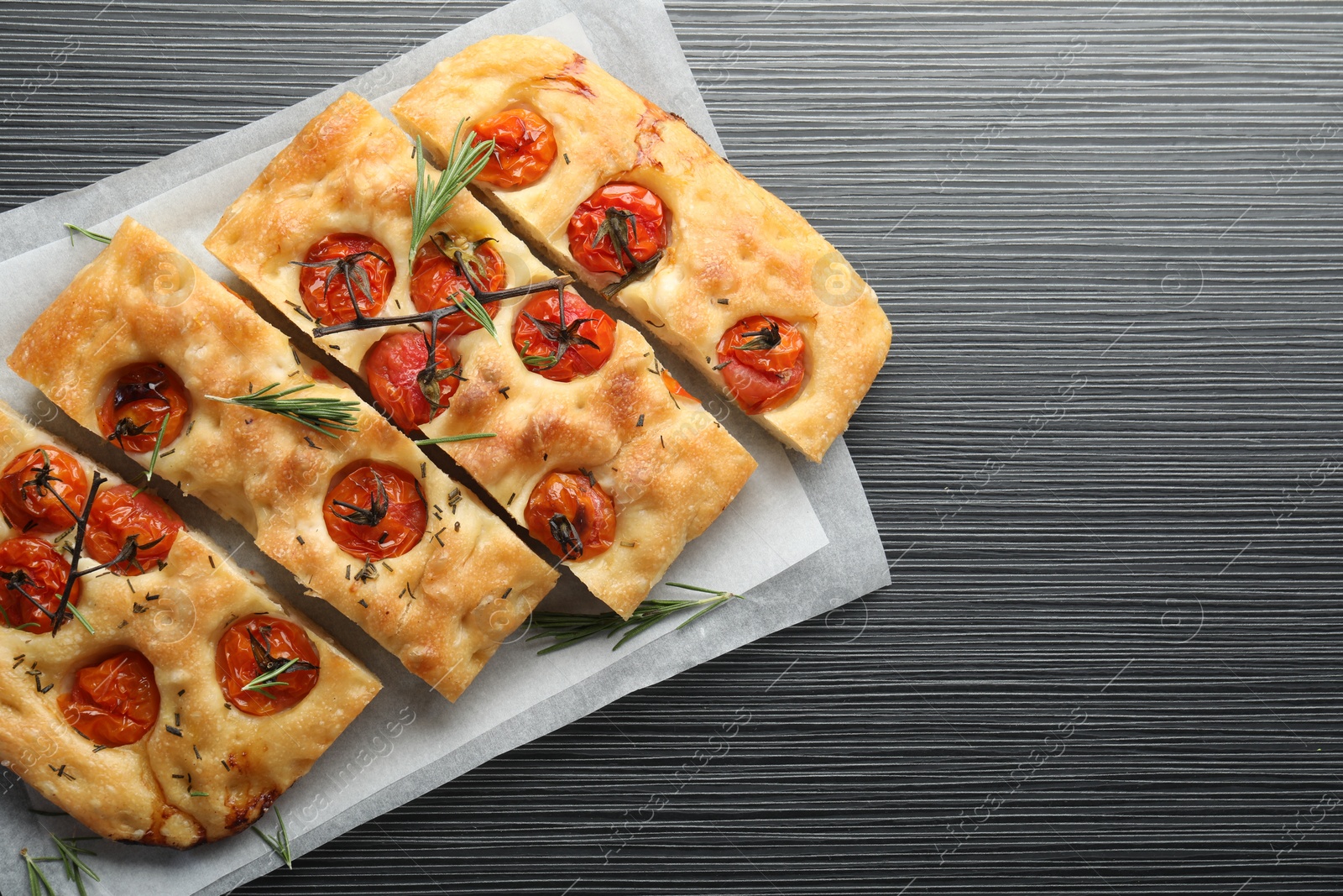 Cut delicious focaccia with tomatoes and spices on dark wooden table, top view. Space for text Photo of Cut delicious focaccia with tomatoes and spices on dark wooden table, top view. Space for text