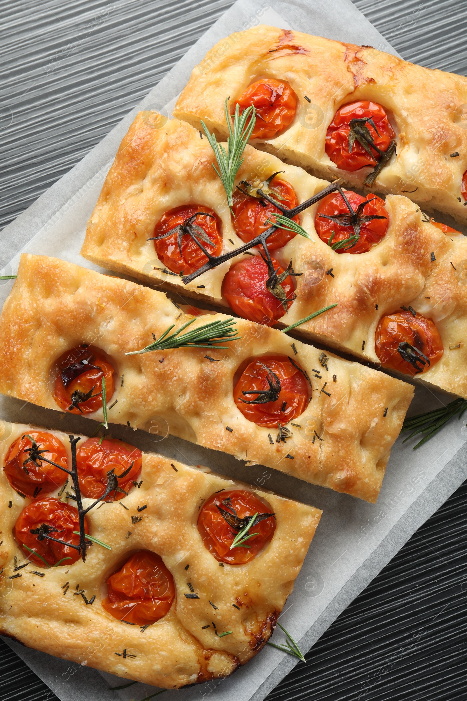 Cut delicious focaccia with tomatoes and spices on dark wooden table, top view Photo of Cut delicious focaccia with tomatoes and spices on dark wooden table, top view