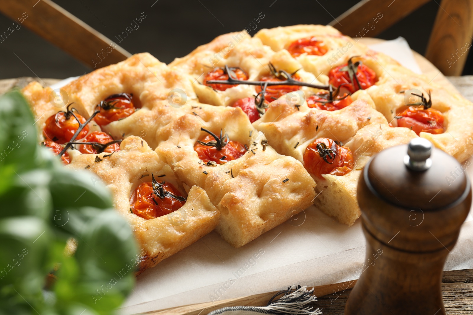 Cut delicious focaccia with tomatoes and spices on table, closeup Photo of Cut delicious focaccia with tomatoes and spices on table, closeup