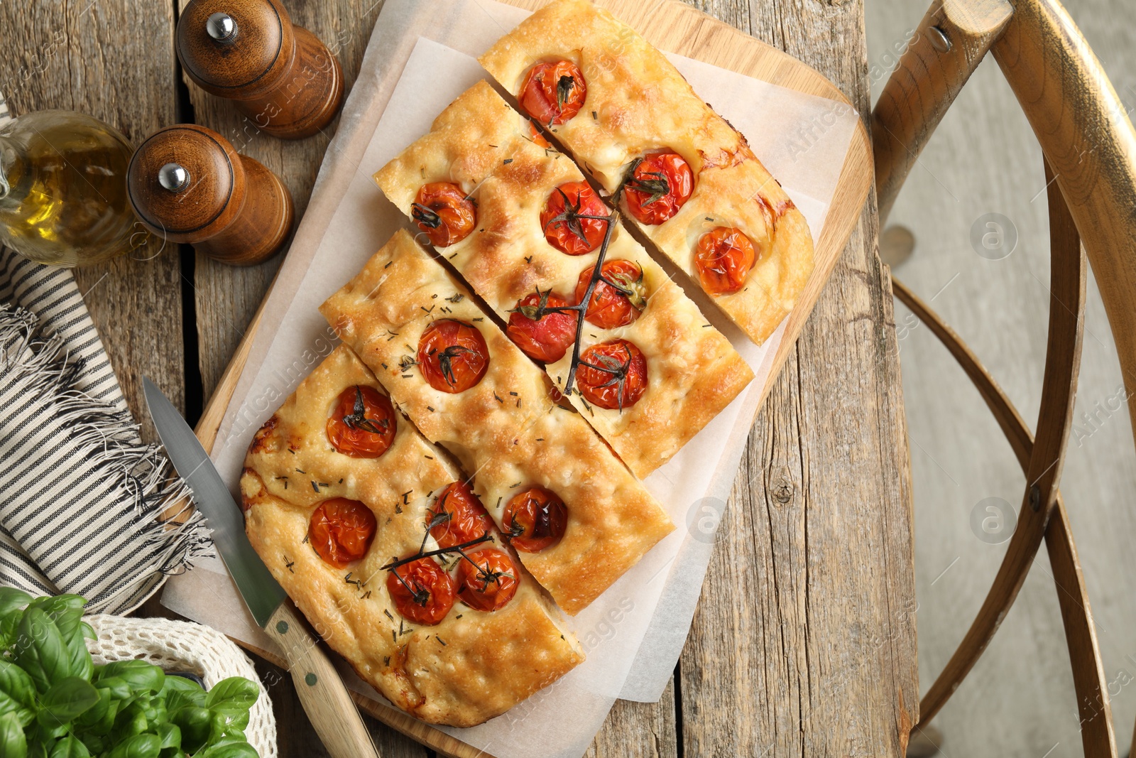 Cut delicious focaccia with tomatoes, spices and oil on wooden table, flat lay Photo of Cut delicious focaccia with tomatoes, spices and oil on wooden table, flat lay
