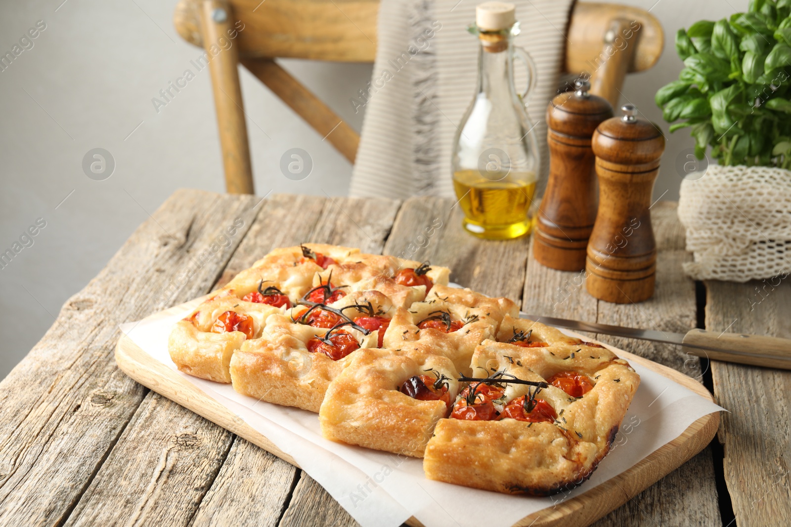 Cut delicious focaccia with tomatoes, spices and oil on wooden table indoors Photo of Cut delicious focaccia with tomatoes, spices and oil on wooden table indoors