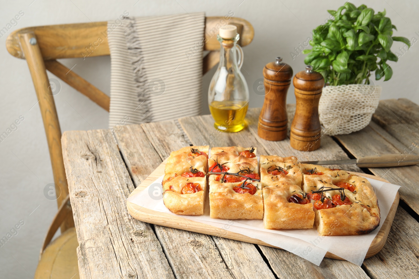 Cut delicious focaccia with tomatoes, spices and oil on wooden table indoors Photo of Cut delicious focaccia with tomatoes, spices and oil on wooden table indoors