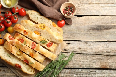 Photo of Cut delicious focaccia with tomatoes, spices and oil on wooden table, flat lay. Space for text