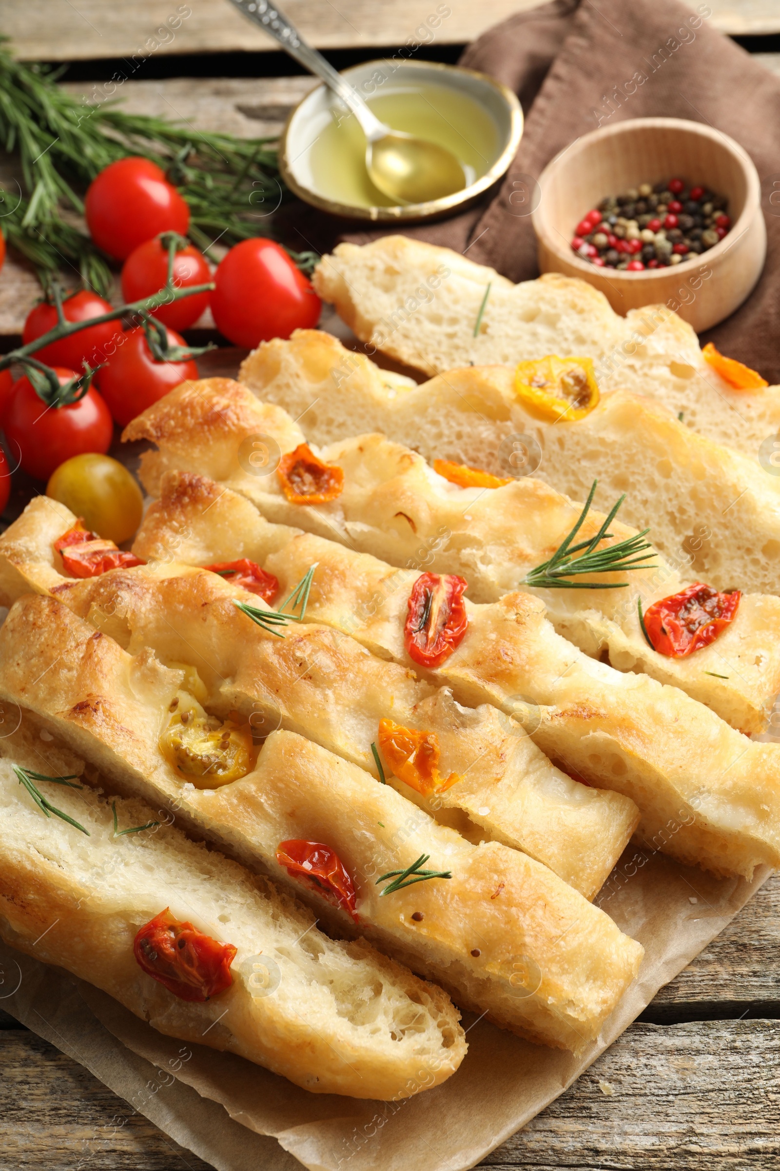 Cut delicious focaccia with tomatoes, spices and oil on wooden table, closeup Photo of Cut delicious focaccia with tomatoes, spices and oil on wooden table, closeup