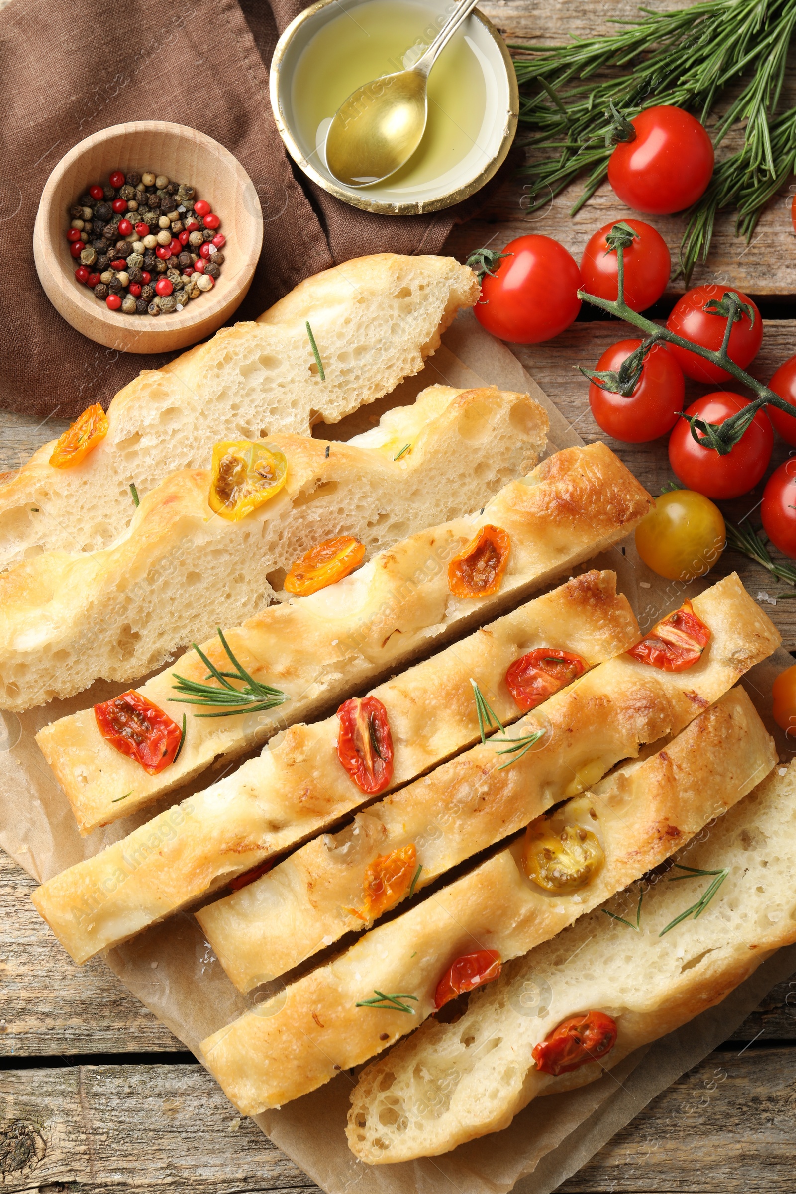 Cut delicious focaccia with tomatoes, spices and oil on wooden table, flat lay Photo of Cut delicious focaccia with tomatoes, spices and oil on wooden table, flat lay