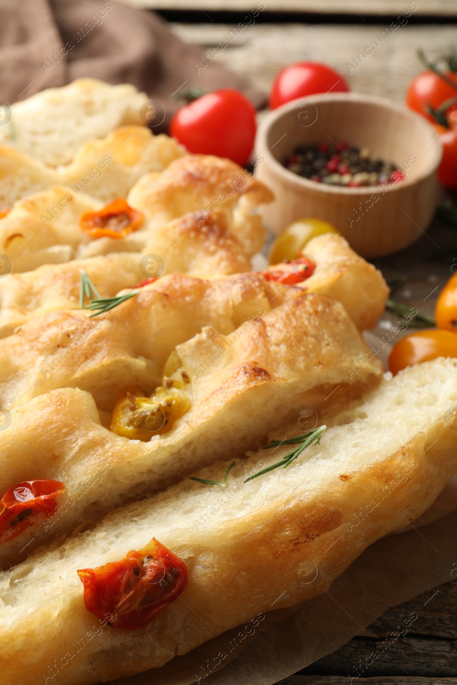 Cut delicious focaccia with tomatoes and rosemary on table, closeup Photo of Cut delicious focaccia with tomatoes and rosemary on table, closeup