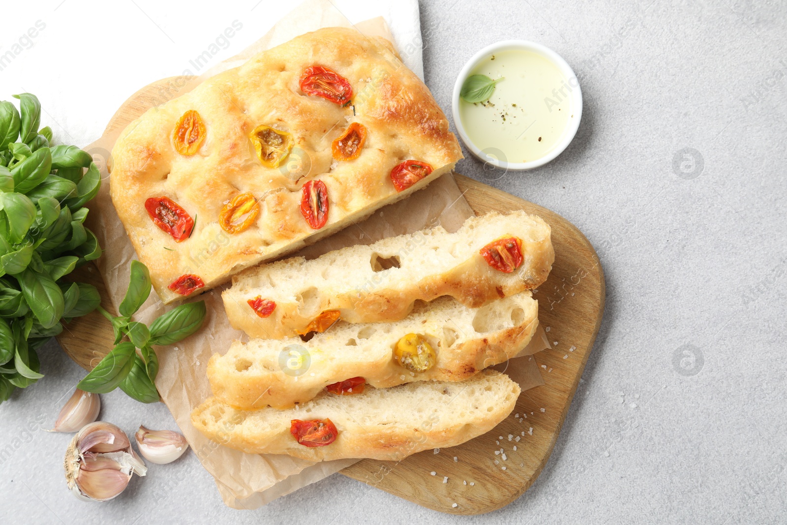 Cut delicious focaccia with tomatoes, spices and oil on gray table, flat lay Photo of Cut delicious focaccia with tomatoes, spices and oil on gray table, flat lay