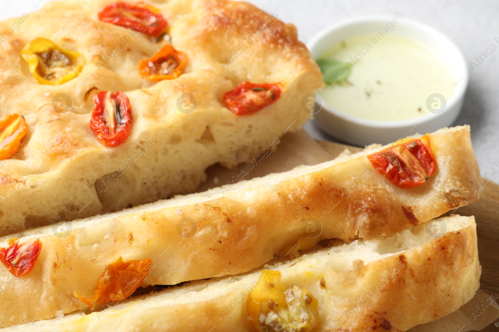 Cut delicious focaccia with tomatoes and oil on gray table, closeup Photo of Cut delicious focaccia with tomatoes and oil on gray table, closeup