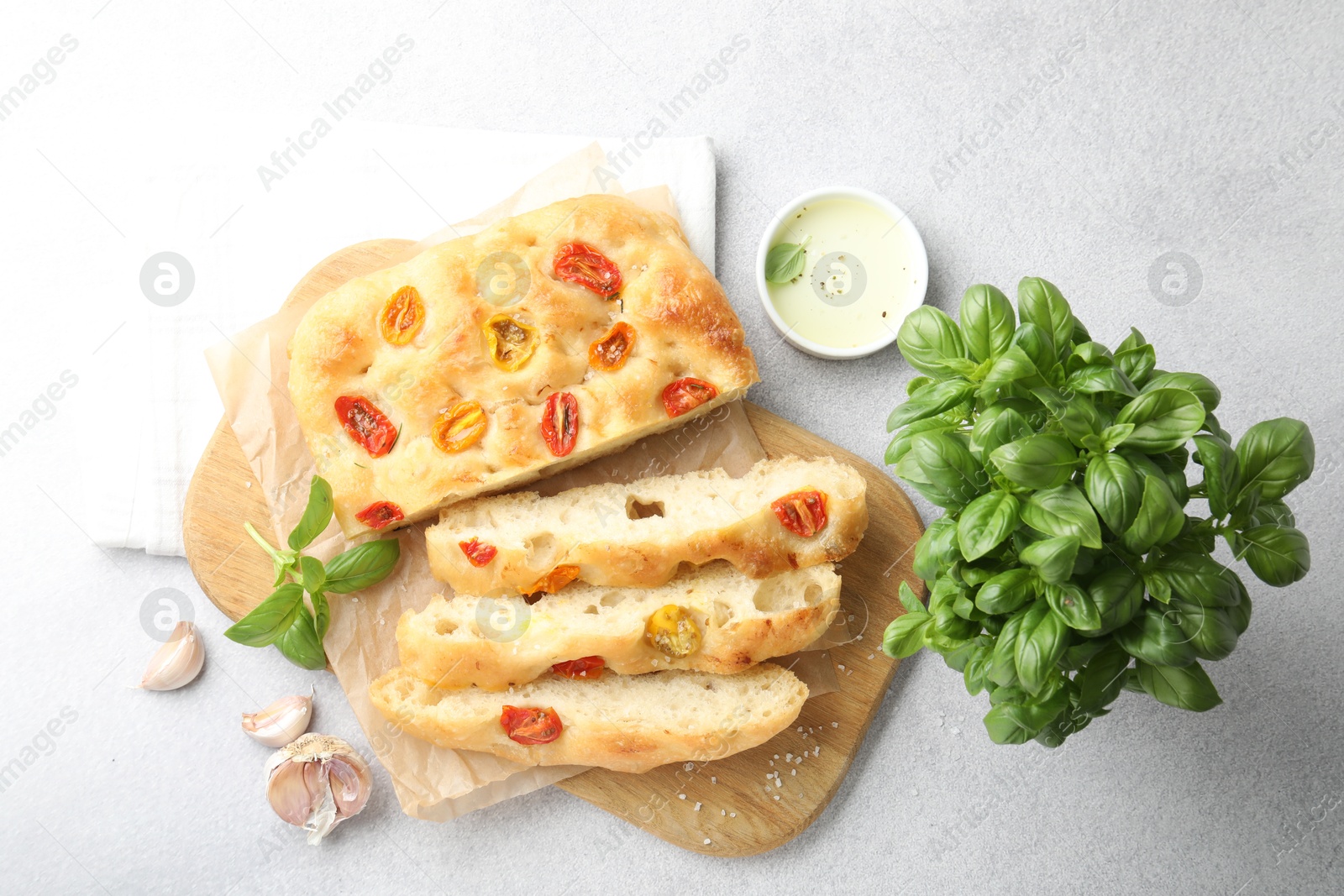 Cut delicious focaccia with tomatoes, spices and oil on gray table, flat lay Photo of Cut delicious focaccia with tomatoes, spices and oil on gray table, flat lay