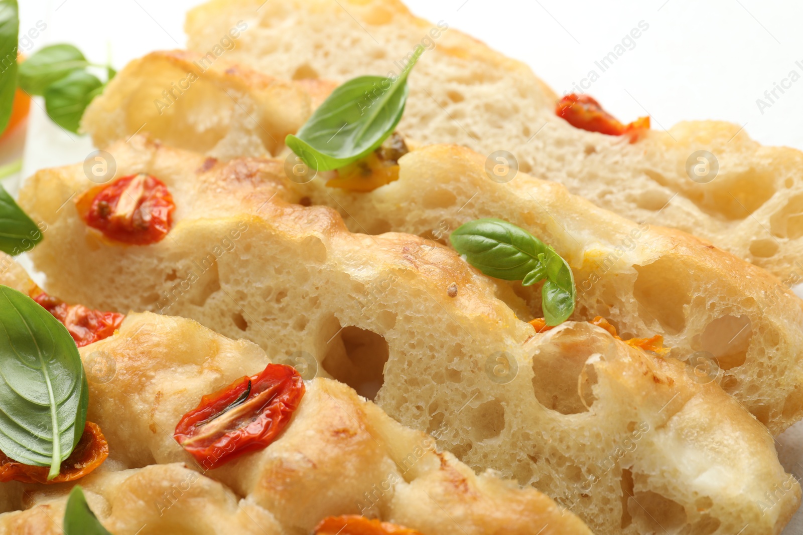 Cut delicious focaccia with tomatoes and basil on table, closeup Photo of Cut delicious focaccia with tomatoes and basil on table, closeup