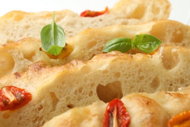 Photo of Cut delicious focaccia with tomatoes and basil on table, closeup