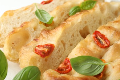 Photo of Cut delicious focaccia with tomatoes and basil on table, closeup