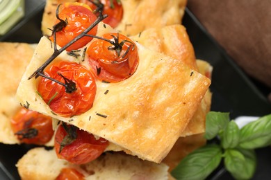 Photo of Pieces of delicious focaccia with tomatoes and spices on table, top view