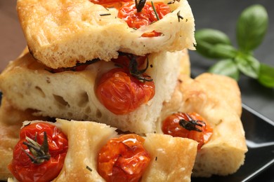 Photo of Pieces of delicious focaccia with tomatoes on table, closeup