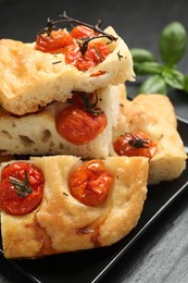Photo of Pieces of delicious focaccia with tomatoes on table, closeup