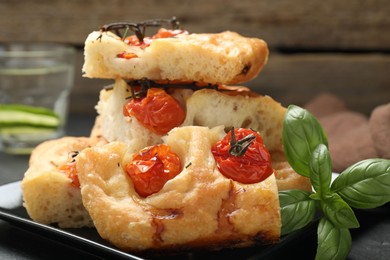 Photo of Pieces of delicious focaccia with tomatoes and spices on table, closeup