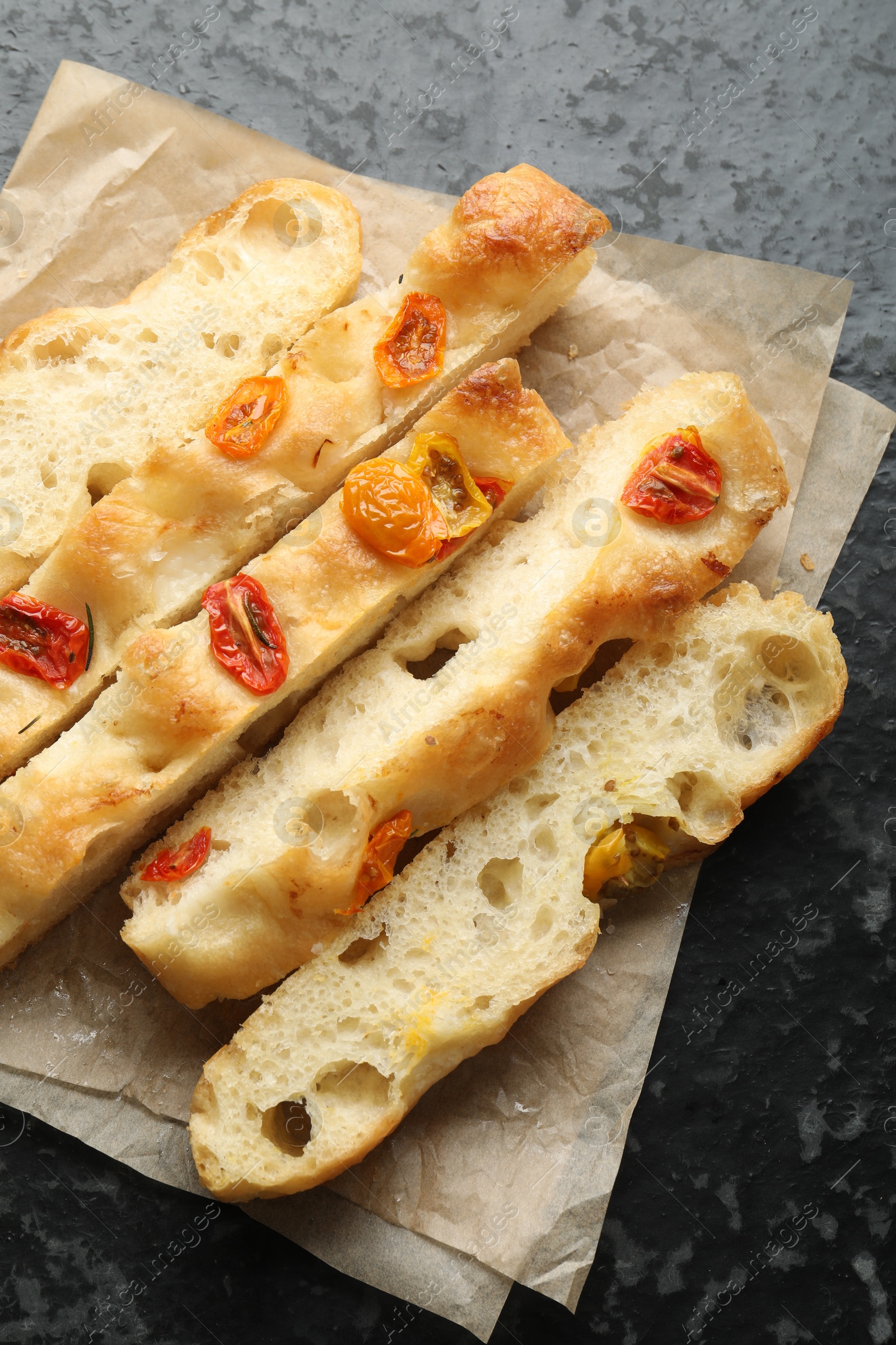 Pieces of delicious focaccia with tomatoes on dark textured table, top view Photo of Pieces of delicious focaccia with tomatoes on dark textured table, top view