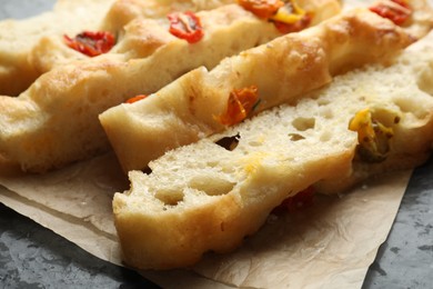 Photo of Pieces of delicious focaccia with tomatoes on table, closeup
