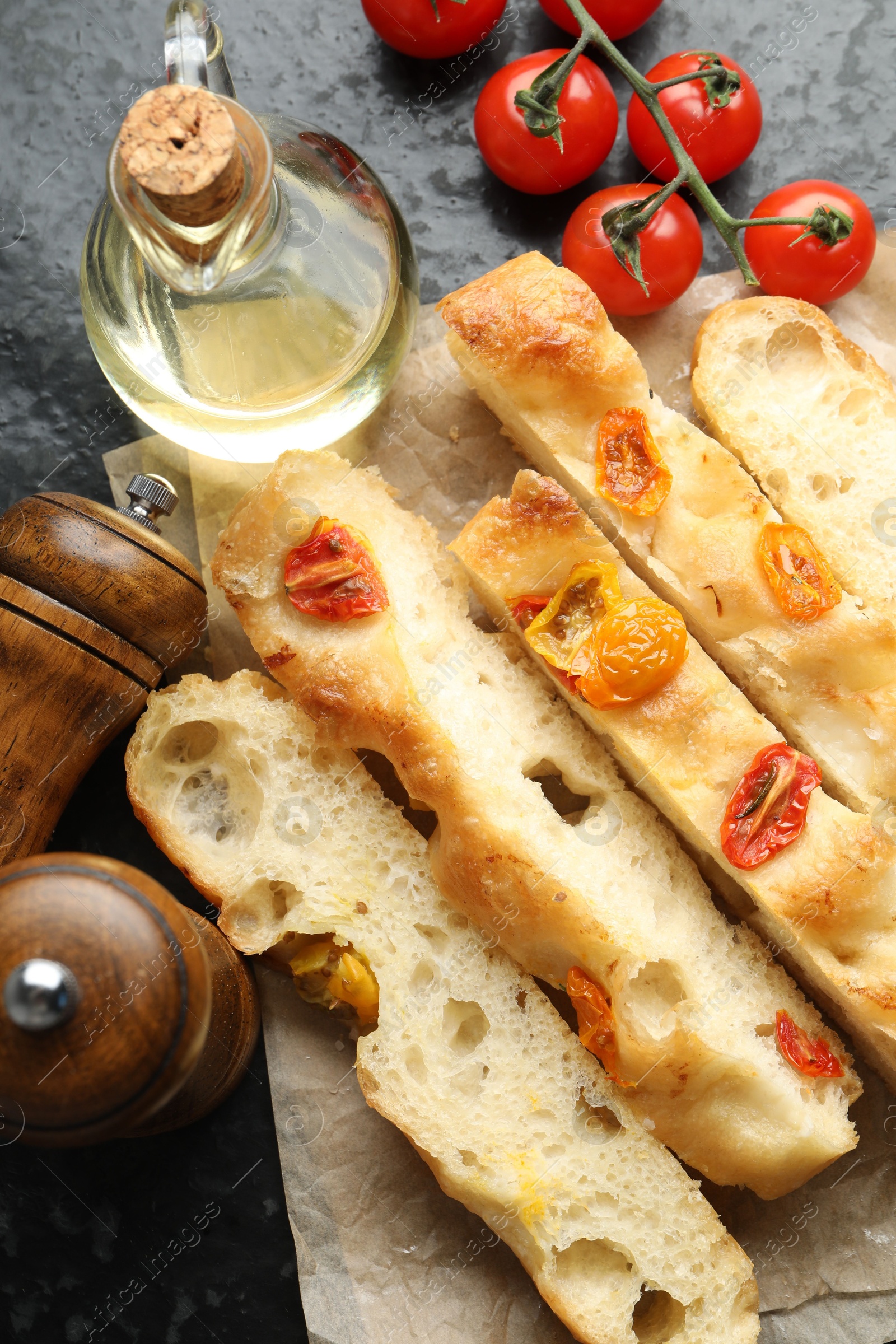 Pieces of delicious focaccia with tomatoes, spices and oil on dark table, flat lay Photo of Pieces of delicious focaccia with tomatoes, spices and oil on dark table, flat lay