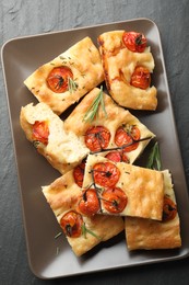 Photo of Pieces of delicious focaccia with tomatoes and spices on gray textured table, top view