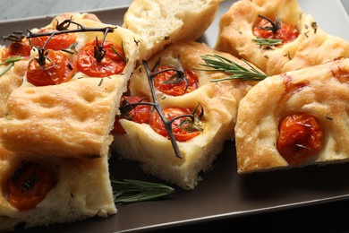 Photo of Pieces of delicious focaccia with tomatoes and spices on table, closeup