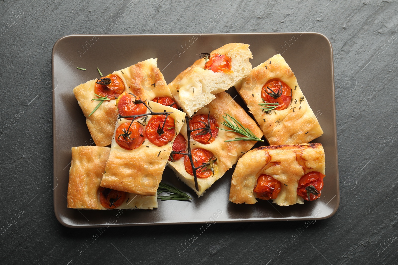 Pieces of delicious focaccia with tomatoes and spices on gray textured table, top view Photo of Pieces of delicious focaccia with tomatoes and spices on gray textured table, top view